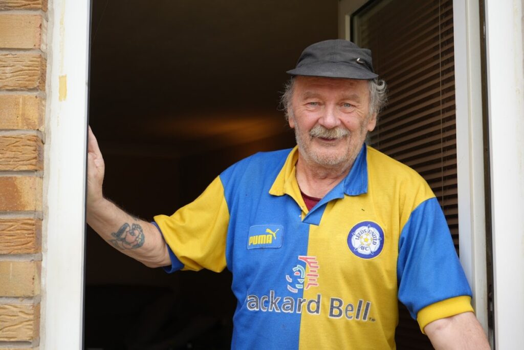 Man happily standing within his doorway.